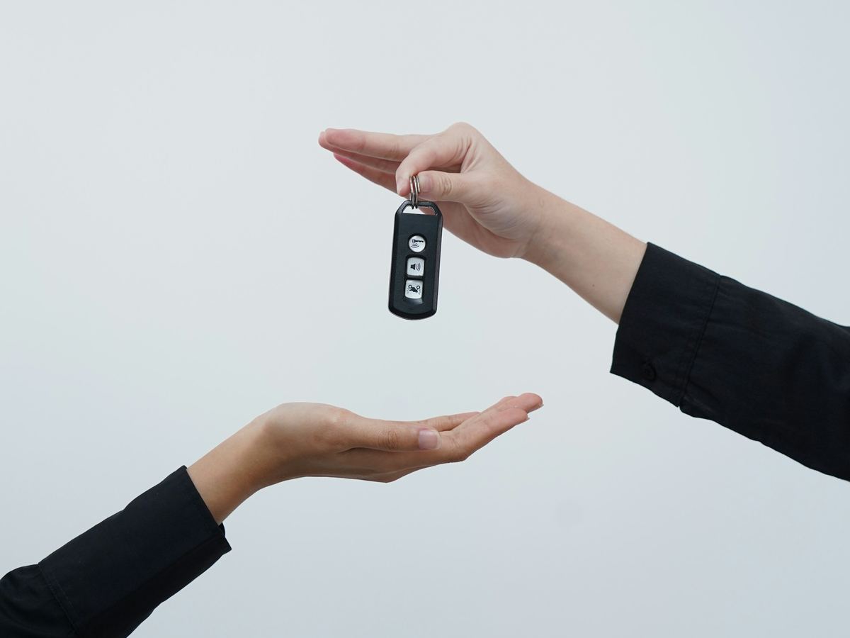 Een hand geeft een autosleutel aan een andere hand